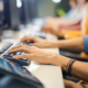 Side view of a person typing on computer while sitting next to many coworkers